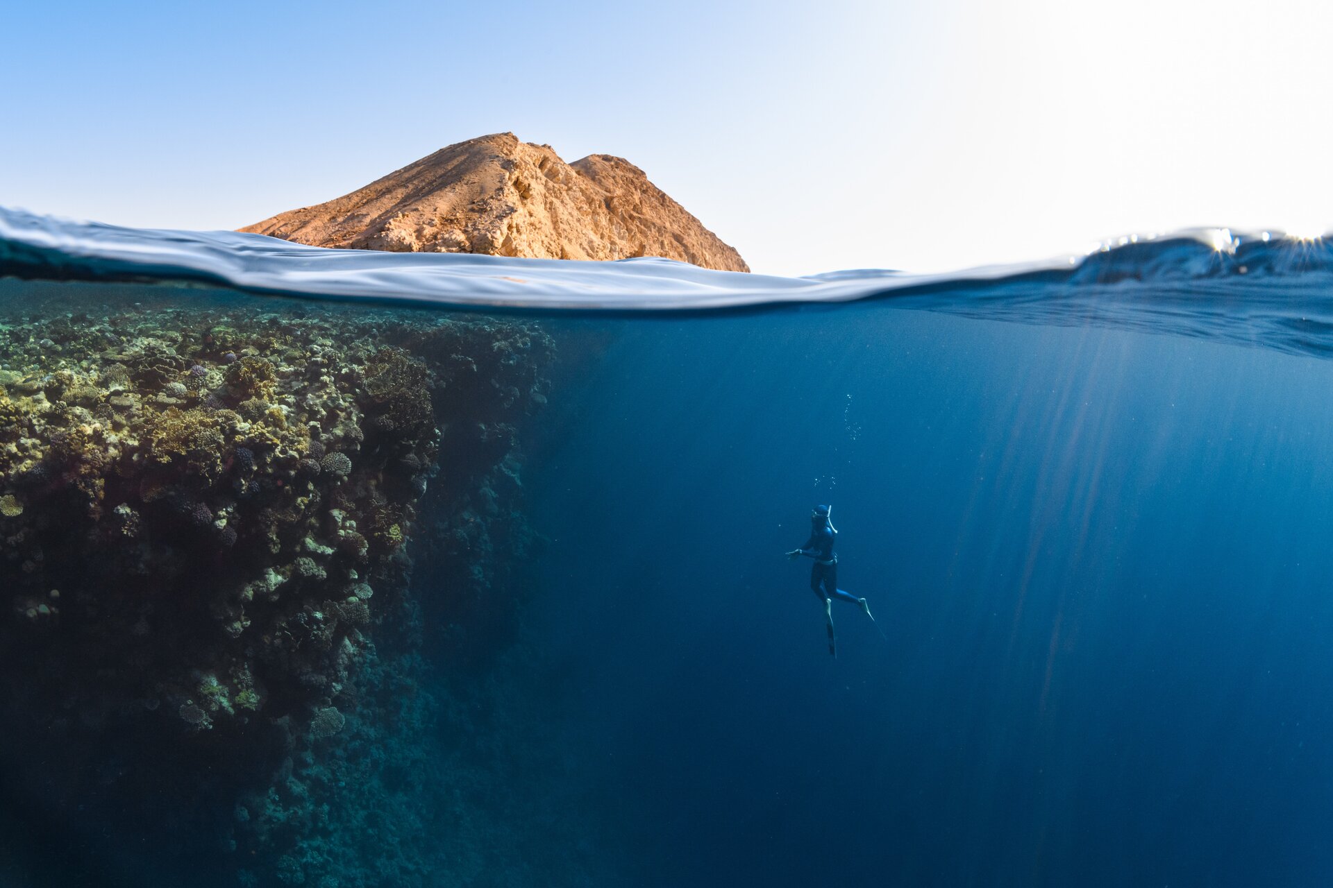 Person swimming deep in water near mountain